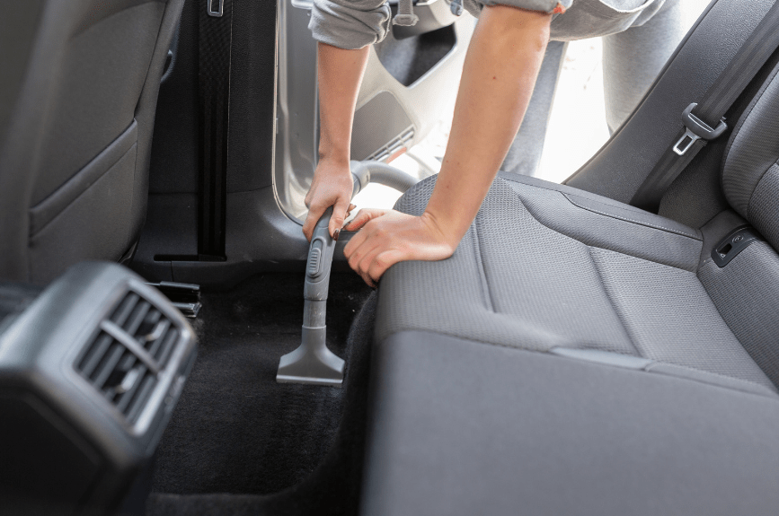 man vacuuming car's interior