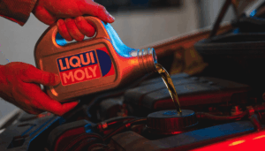 Mechanic pouring Liqui Moly engine oil into a car engine