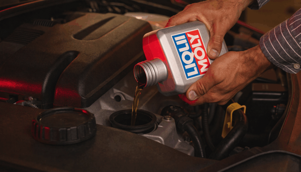 Mechanic pouring Liqui Moly engine oil into an open car engine oil filler